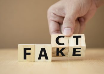 Eine Hand dreht Holzklötzchen mit Buchstaben von Fake auf Fact