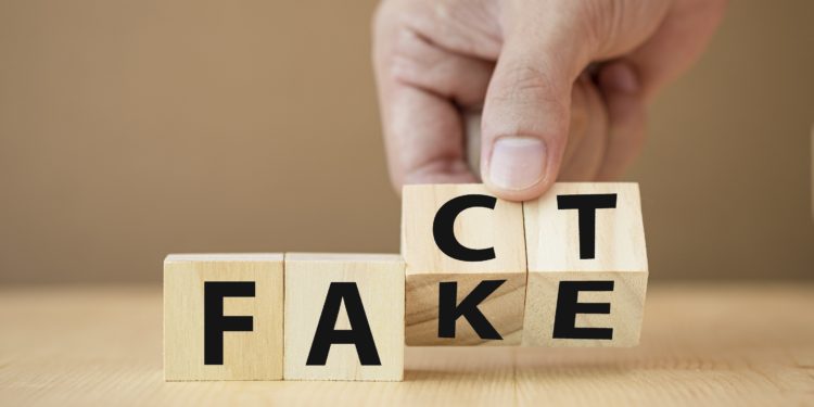 Eine Hand dreht Holzklötzchen mit Buchstaben von Fake auf Fact