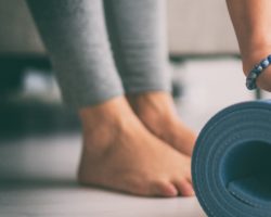 Frau rollt eine Fitnessmatte in der Wohnung aus