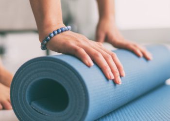 Frau rollt eine Fitnessmatte in der Wohnung aus