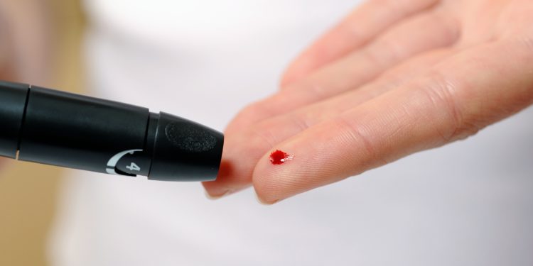 Hand mit Blutstropfen am Finger zur Blutzuckermessung