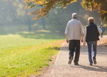 Ältere Paar geht im herbstlichen Park spazieren