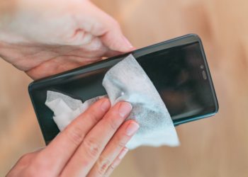 Bildschirm eines Smartphones wird mit einem Tuch sauber gewischt