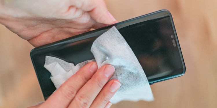 Bildschirm eines Smartphones wird mit einem Tuch sauber gewischt