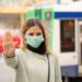 Frau mit medizinischer Gesichtsmaske macht mit der Hand das Zeichen, von ihr weg zu bleiben