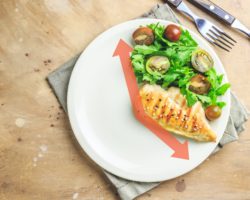 Ein Teller ist zu zwei Drittel leer und zu einem Drittel mt Hähnchenbrust und Salat belegt.