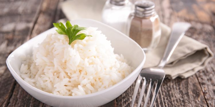 Eine kleine Schüssel gekochter Reis mit Gabel, Salz und Pfeffer auf einem Tisch