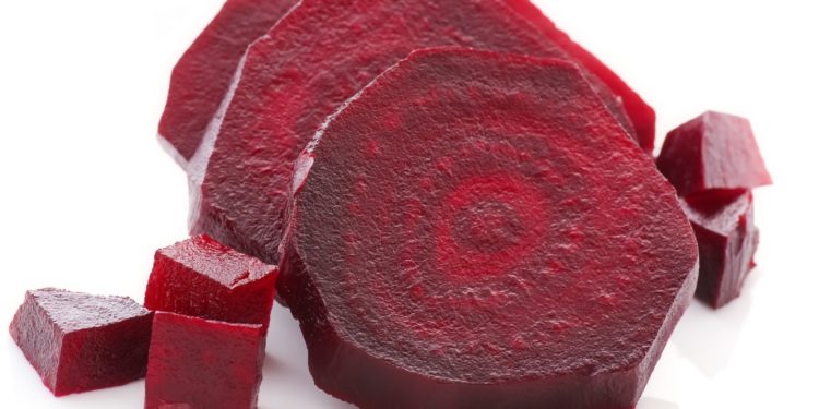 Rote Beete in Scheiben und kleine Würfel geschnitten auf weißem Grund.