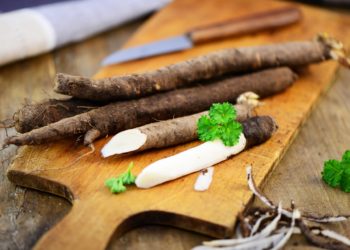 Schwarzwurzeln und ein Messer auf einem hölzernen Schneidebrett