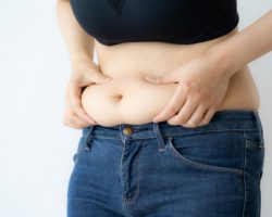 Übergewichtige Frau drückt ihren dicken Bauch