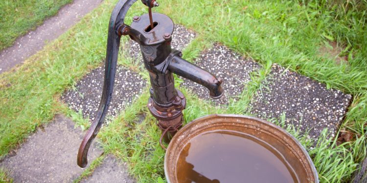 Alte Wasserpumpe mit Zinkwanne in einem Garten