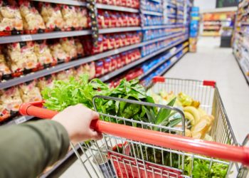 Kunde schiebt Einkaufswagen durch den Gang eines Supermarkts