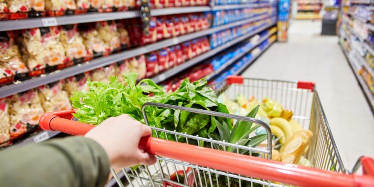 Kunde schiebt Einkaufswagen durch den Gang eines Supermarkts