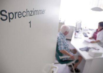 Ein Mann sitzt in einem Sprechzimmer in einer Arztpraxis.