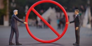 Zwei Figuren werden durch ein großes Verbotsschild daran gehindert, sich die Hand zu reichen.