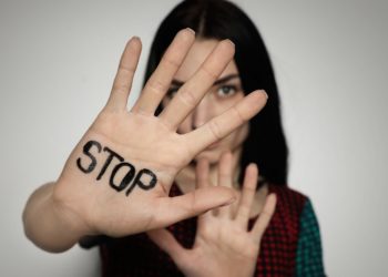 Frau hält ihre rechte Handfläche vor das Gesicht, auf der STOP geschrieben steht