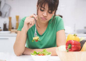 Eine Frau stochert appetitlos in ihrem Essen herum.