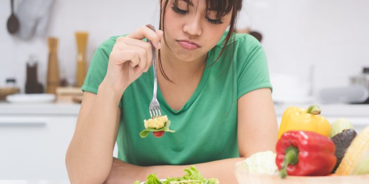 Eine Frau stochert appetitlos in ihrem Essen herum.