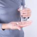 Frau hält in einer Hand ein Glas Wasser und in der anderen zwei Tabletten