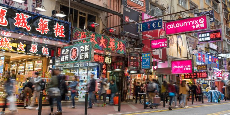 Eine belebte Straße in Hongkong mit vielen Geschäften und Leuchtreklamen.