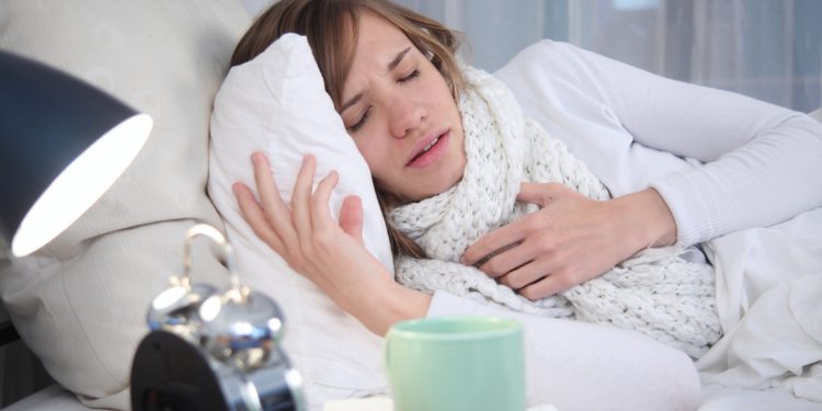 Eine junge Frau liegt krank im Bett.