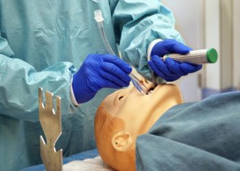 Eine Person in Schutzausrüstung führt eine maschinelle Beatmung an einem Dummy durch.