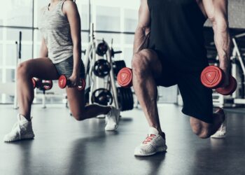 Frau und Mann trainieren im Fitnessstudio mit Hanteln