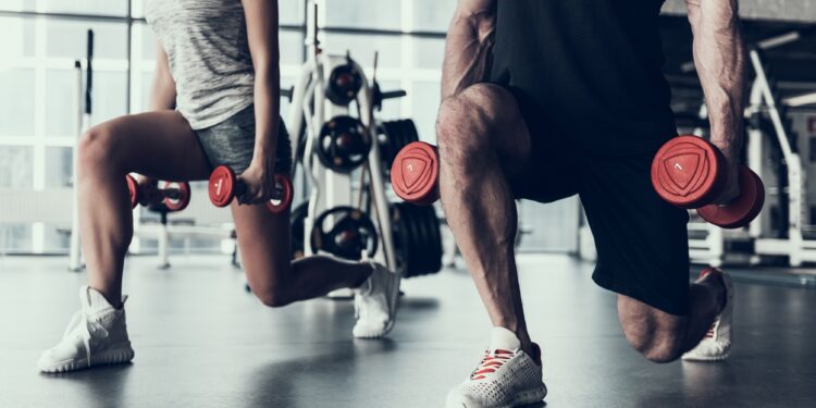 Frau und Mann trainieren im Fitnessstudio mit Hanteln