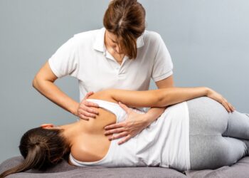 Therapeutin behandelt den Rücken einer Patientin manuell