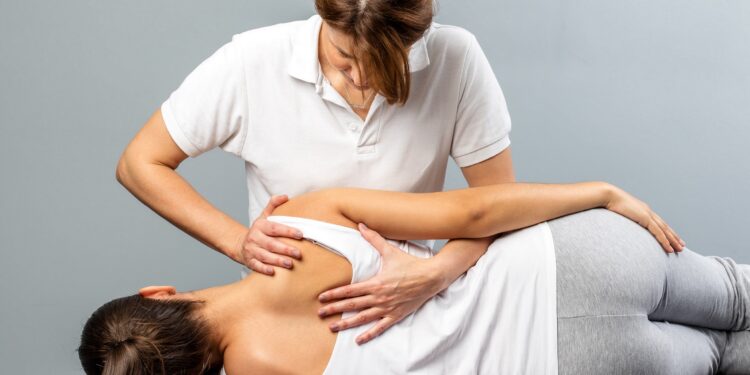 Therapeutin behandelt den Rücken einer Patientin manuell