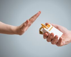 Eine Person reagiert mit einer ablehnenden Geste als ihr Zigaretten angeboten werden.