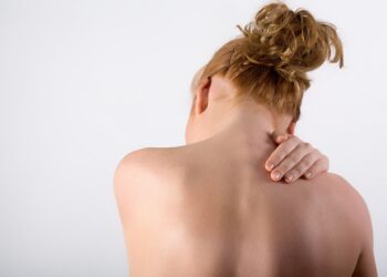Frau hält sich vor Schmerzen den Rücken.
