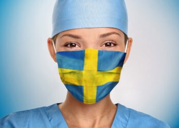 Eine Frau trägt eine Mund-Nasenschutzmaske in den Farben der schwedischen Flagge.