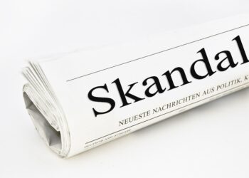 Auf der Titelseite einer Zeitung steht das Wort "Skandal".
