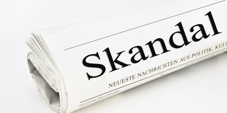 Auf der Titelseite einer Zeitung steht das Wort "Skandal".