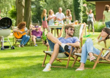 Junge Menschen bei einer Grillveranstaltung auf einer Wiese.