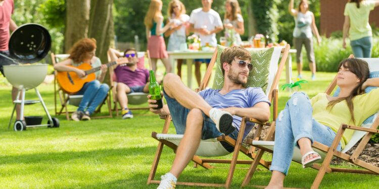 Junge Menschen bei einer Grillveranstaltung auf einer Wiese.