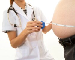 Ärztin misst Bauchumfang eines adipösen Patienten.