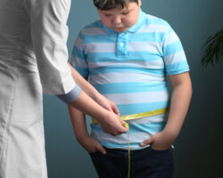 Eine Ärztin misst den Bauchumfang bei einem übergewichtigen Jungen.