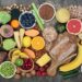 Eine Tischplatte voller pflanzlicher Lebensmittel wie Obst, Gemüse, Hülsenfrüchten und Vollkornprodukten
