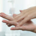 Weibliche Hände verreiben Desinfektionsmittel