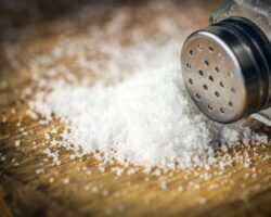 Verschüttetes Salz und Salzstreuer auf einer Holzunterlage