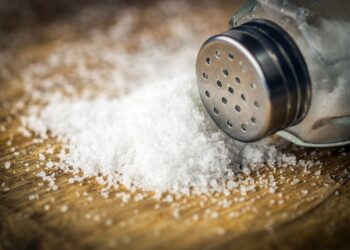 Verschüttetes Salz und Salzstreuer auf einer Holzunterlage