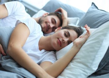 Ein glücklich wirkendes Paar schläft nebeneinander im Bett