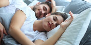 Ein glücklich wirkendes Paar schläft nebeneinander im Bett