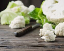 Frischer roher Blumenkohl und ein Messer auf einem Holztisch