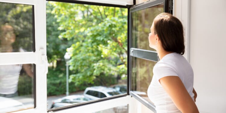 Frau öffnet Fenster zum Lüften