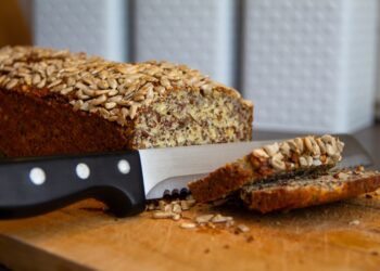 Eiweißbrot mit Brotmesser und zwei Brotscheiben auf einem Holzbrett