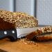 Eiweißbrot mit Brotmesser und zwei Brotscheiben auf einem Holzbrett