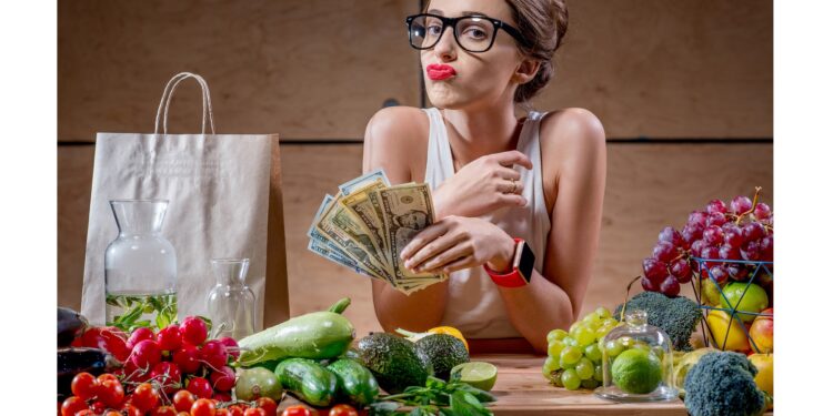 Eine Frau hat ein Bündel Geld in der Hand und vor ihr liegen gesunde Lebensmittel.